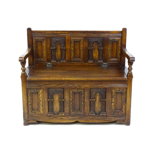 1673 - An early 20thC Old Charm monks bench with a chamfered frame, carved oak panels and a hinged seat. 39... 