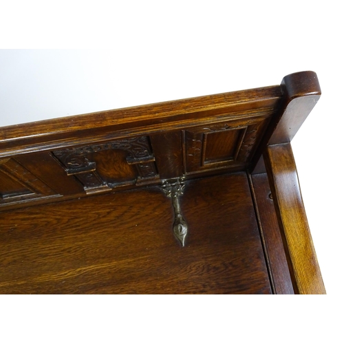 1673 - An early 20thC Old Charm monks bench with a chamfered frame, carved oak panels and a hinged seat. 39... 