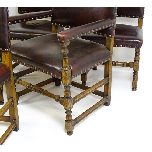 1684 - A set of six early 20thC oak and leather dining chairs with studwork detailing and raised on block a... 