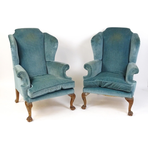 1691 - A pair of early 20thC wingback armchairs with scrolled arms and raised on acanthus carved cabriole f... 