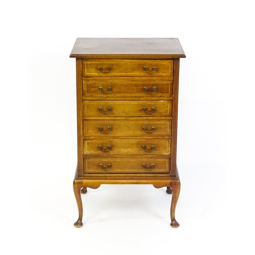 1718 - An Edwardian mahogany music cabinet with six short drawers with fall fronts and raised on four cabri... 