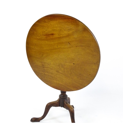 1737 - A Georgian mahogany tripod table with a circular tilt top above a turned pedestal and three cabriole... 