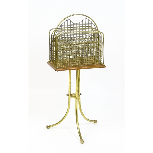 1743 - An early / mid 20thC brass and oak revolving magazine rack raised on three splayed legs. 35 1/2