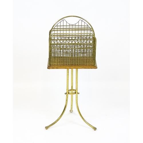 1743 - An early / mid 20thC brass and oak revolving magazine rack raised on three splayed legs. 35 1/2