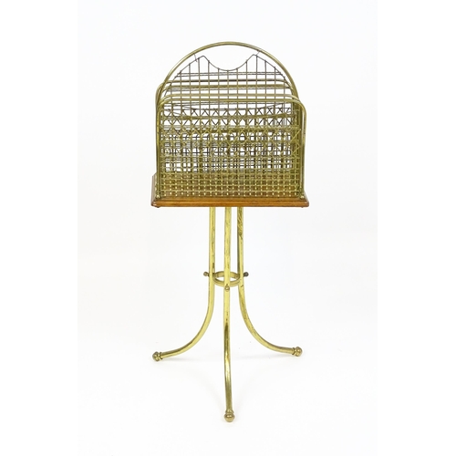 1743 - An early / mid 20thC brass and oak revolving magazine rack raised on three splayed legs. 35 1/2