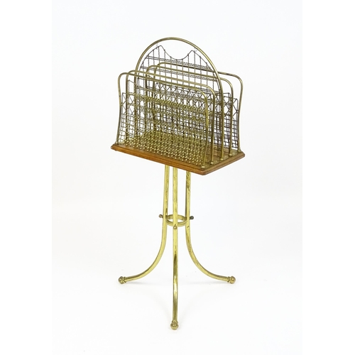 1743 - An early / mid 20thC brass and oak revolving magazine rack raised on three splayed legs. 35 1/2