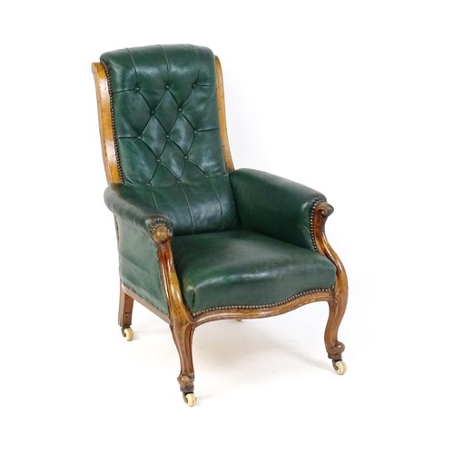 1692 - A Victorian green leather armchair with a deep buttoned backrest, scrolled arms and a moulded frame,... 