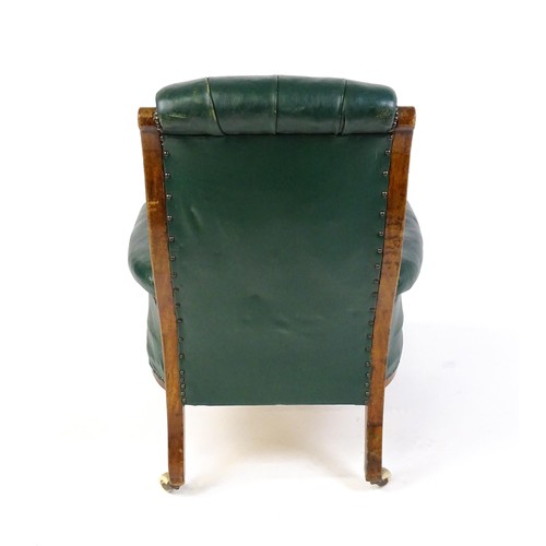 1692 - A Victorian green leather armchair with a deep buttoned backrest, scrolled arms and a moulded frame,... 