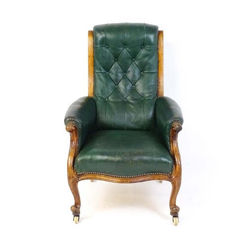 1692 - A Victorian green leather armchair with a deep buttoned backrest, scrolled arms and a moulded frame,... 