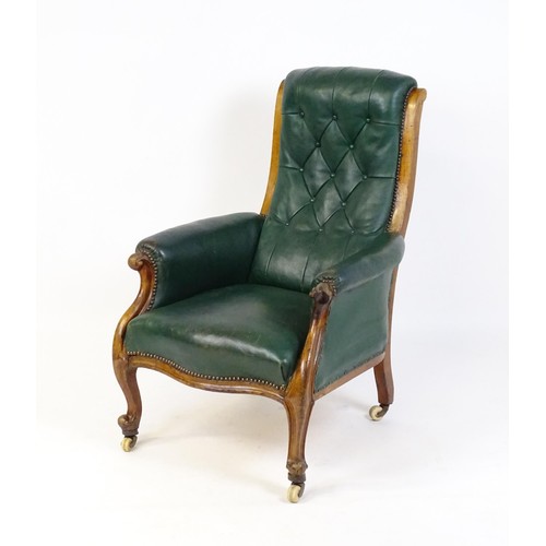 1692 - A Victorian green leather armchair with a deep buttoned backrest, scrolled arms and a moulded frame,... 