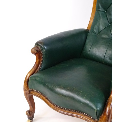 1692 - A Victorian green leather armchair with a deep buttoned backrest, scrolled arms and a moulded frame,... 