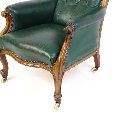 1692 - A Victorian green leather armchair with a deep buttoned backrest, scrolled arms and a moulded frame,... 