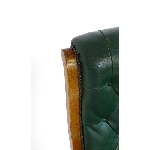 1692 - A Victorian green leather armchair with a deep buttoned backrest, scrolled arms and a moulded frame,... 