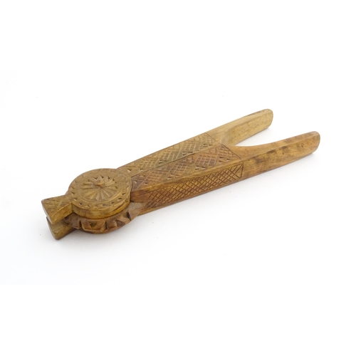 1130 - Treen: A 19thC Scandinavian fruitwood nutcracker with tapering handles and chip carved decoration to... 