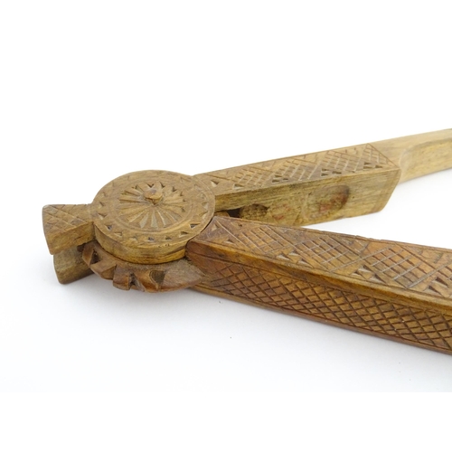 1130 - Treen: A 19thC Scandinavian fruitwood nutcracker with tapering handles and chip carved decoration to... 