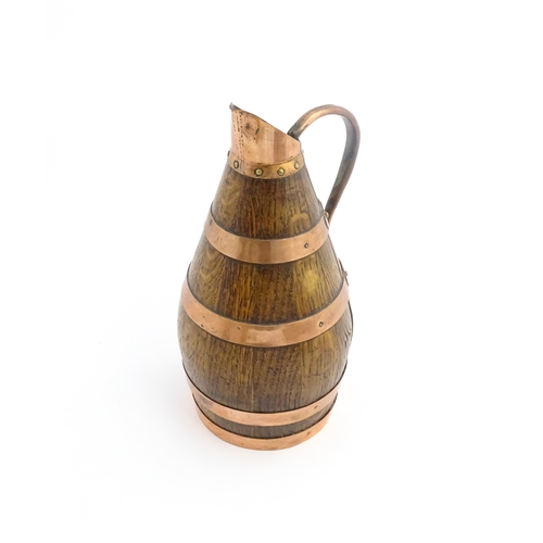 1141 - An early 20thC coopered oak and copper cider jug / flagon. Approx. 10 1/2