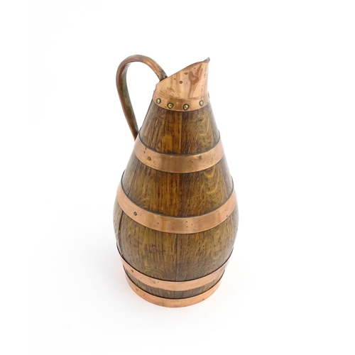 1141 - An early 20thC coopered oak and copper cider jug / flagon. Approx. 10 1/2