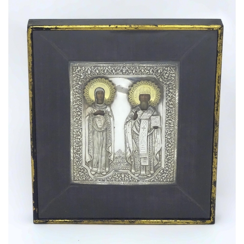 1067 - A 19thC Russian Orthodox icon with embossed silver surround and oil on panel depictions of two saint... 