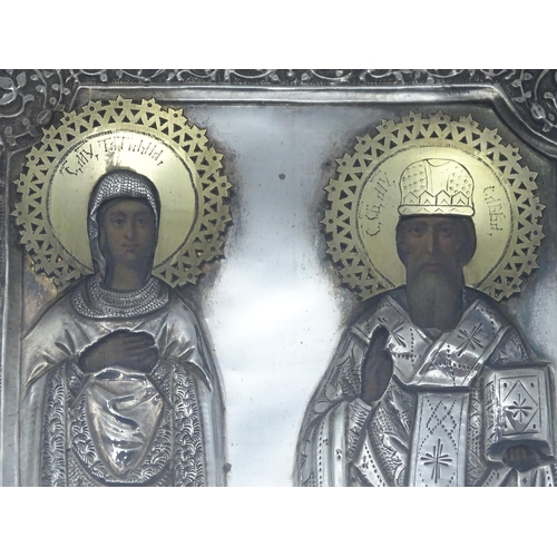 1067 - A 19thC Russian Orthodox icon with embossed silver surround and oil on panel depictions of two saint... 