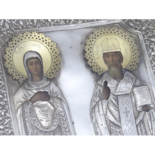 1067 - A 19thC Russian Orthodox icon with embossed silver surround and oil on panel depictions of two saint... 