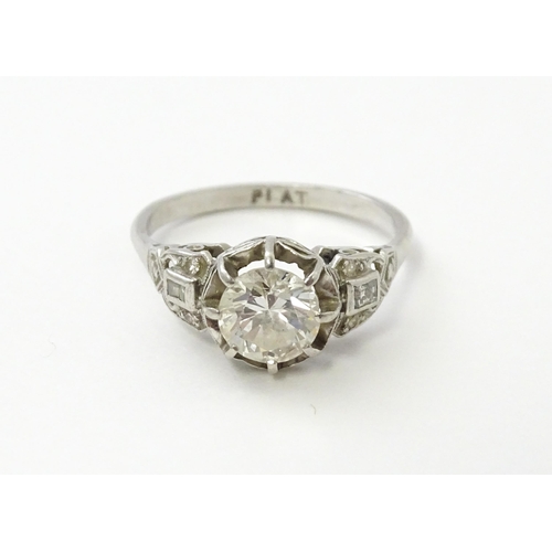 541 - A platinum ring set with central claw set brilliant cut diamond flanked by further diamonds to shoul... 