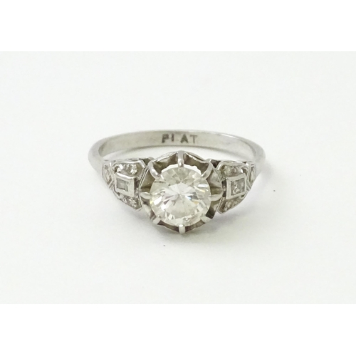 541 - A platinum ring set with central claw set brilliant cut diamond flanked by further diamonds to shoul... 