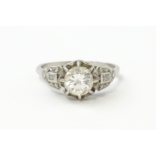 541 - A platinum ring set with central claw set brilliant cut diamond flanked by further diamonds to shoul... 