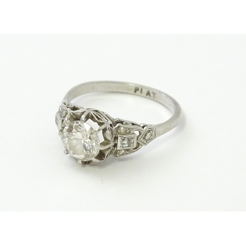 541 - A platinum ring set with central claw set brilliant cut diamond flanked by further diamonds to shoul... 