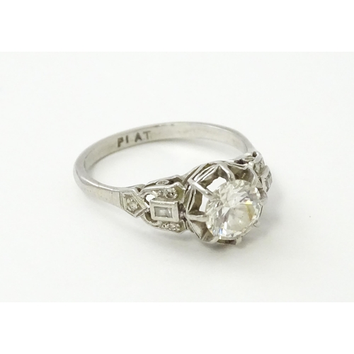 541 - A platinum ring set with central claw set brilliant cut diamond flanked by further diamonds to shoul... 