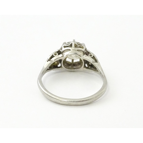 541 - A platinum ring set with central claw set brilliant cut diamond flanked by further diamonds to shoul... 