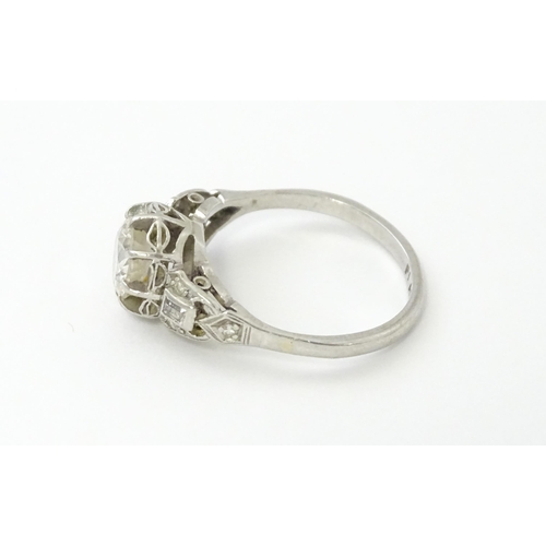 541 - A platinum ring set with central claw set brilliant cut diamond flanked by further diamonds to shoul... 