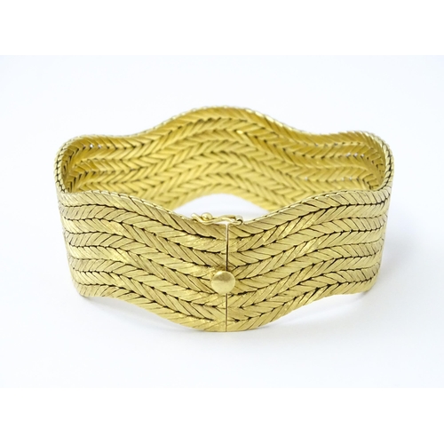 581 - An 18ct gold bracelet formed as eight rows, with textured chevron pattern, box snap clasp and safety... 