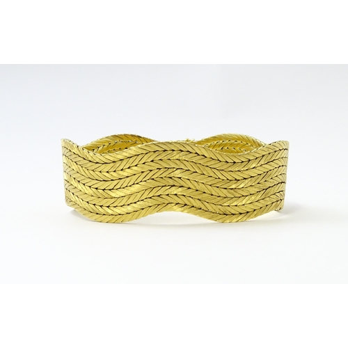 581 - An 18ct gold bracelet formed as eight rows, with textured chevron pattern, box snap clasp and safety... 