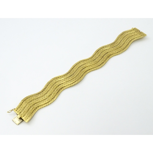 581 - An 18ct gold bracelet formed as eight rows, with textured chevron pattern, box snap clasp and safety... 