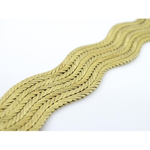 581 - An 18ct gold bracelet formed as eight rows, with textured chevron pattern, box snap clasp and safety... 