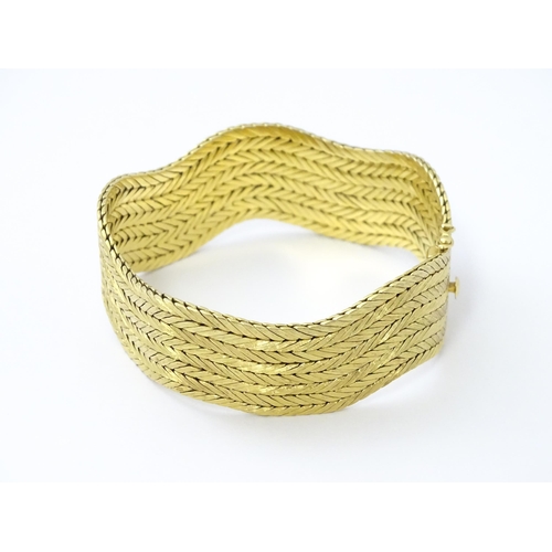 581 - An 18ct gold bracelet formed as eight rows, with textured chevron pattern, box snap clasp and safety... 