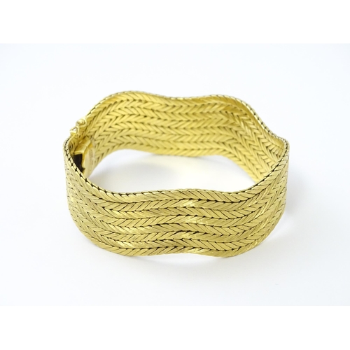 581 - An 18ct gold bracelet formed as eight rows, with textured chevron pattern, box snap clasp and safety... 