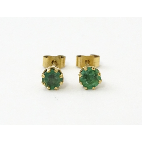 582 - A pair of 9ct gold stud earrings set with emeralds. Approx. 1/8