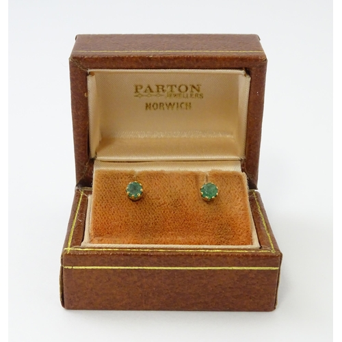 582 - A pair of 9ct gold stud earrings set with emeralds. Approx. 1/8