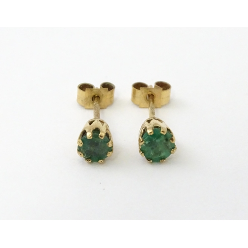 582 - A pair of 9ct gold stud earrings set with emeralds. Approx. 1/8