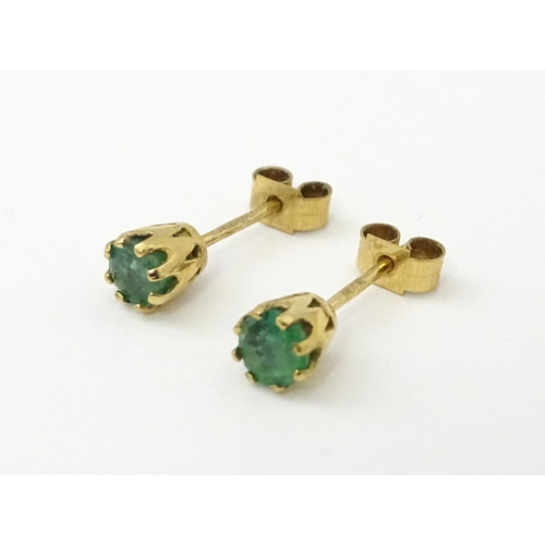 582 - A pair of 9ct gold stud earrings set with emeralds. Approx. 1/8