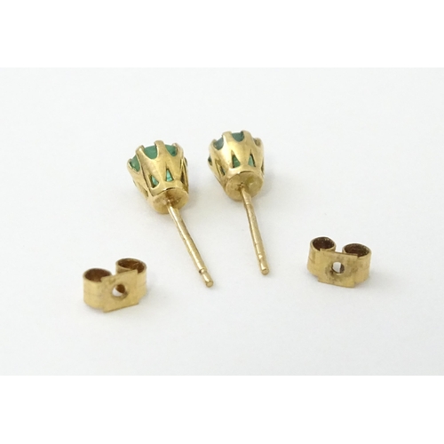 582 - A pair of 9ct gold stud earrings set with emeralds. Approx. 1/8