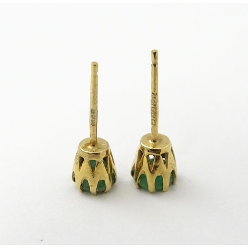 582 - A pair of 9ct gold stud earrings set with emeralds. Approx. 1/8