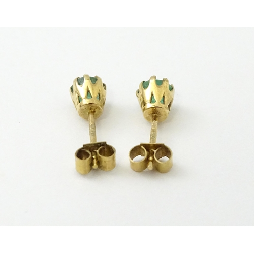 582 - A pair of 9ct gold stud earrings set with emeralds. Approx. 1/8