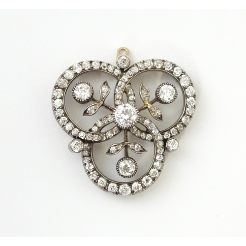 583 - A yellow gold brooch / pendant of trefoil form set with a profusion of diamonds with floral detail. ... 