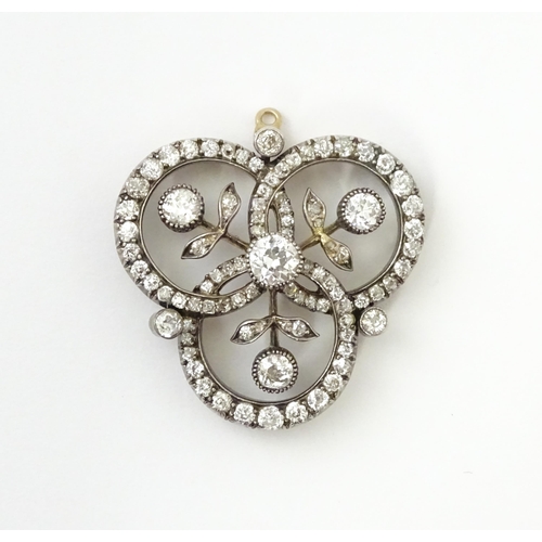 583 - A yellow gold brooch / pendant of trefoil form set with a profusion of diamonds with floral detail. ... 