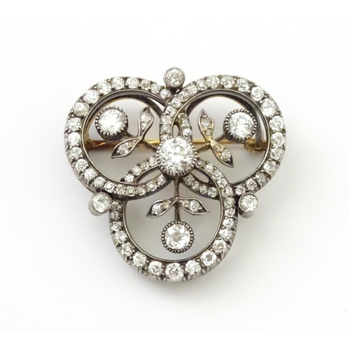 583 - A yellow gold brooch / pendant of trefoil form set with a profusion of diamonds with floral detail. ... 