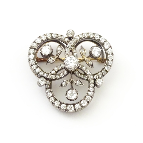 583 - A yellow gold brooch / pendant of trefoil form set with a profusion of diamonds with floral detail. ... 