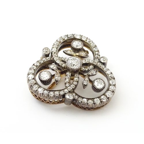 583 - A yellow gold brooch / pendant of trefoil form set with a profusion of diamonds with floral detail. ... 