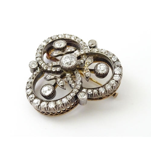 583 - A yellow gold brooch / pendant of trefoil form set with a profusion of diamonds with floral detail. ... 